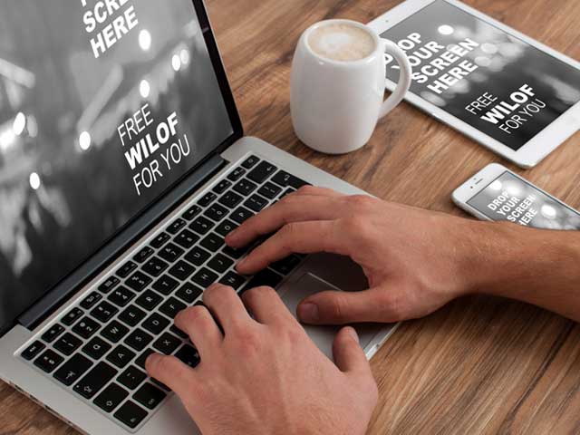 person working on different devices having coffee on table